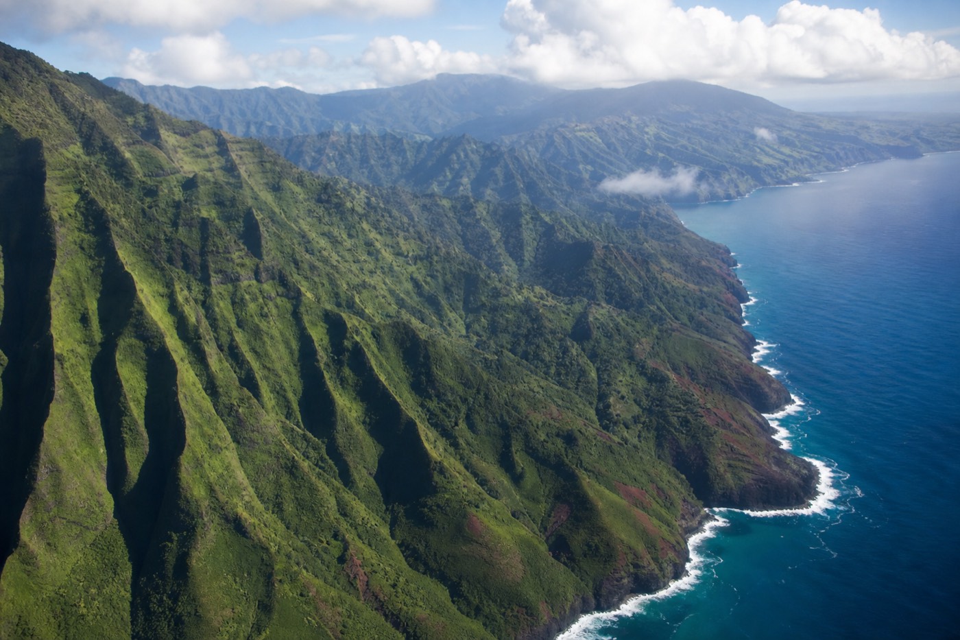 A helicopter and a small high-wing airplane over the cliffs of Kauai's Nā Pali Coast