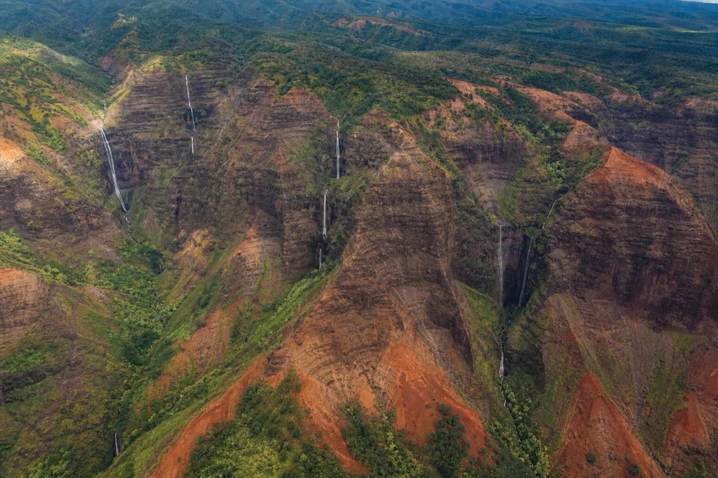 Turbine helicopter banking over the red walls and green ridges of Waimea Canyon on Kauai