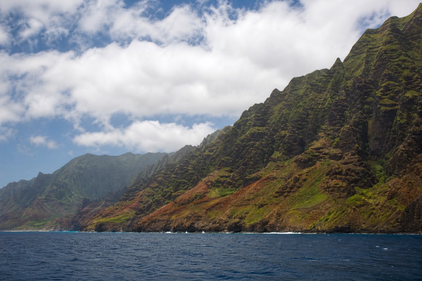 Emerald fluted cliffs of the Nā Pali Coast seen from a catamaran on the Pacific off Kauai
